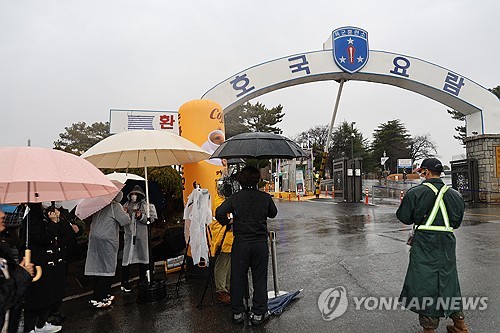Los fanes de BTS esperan a RM y V bajo la lluvia, el 11 de diciembre de 2023, frente a un campamento de entrenamiento militar en Nonsan, en la provincia del Chungcheong del Sur.